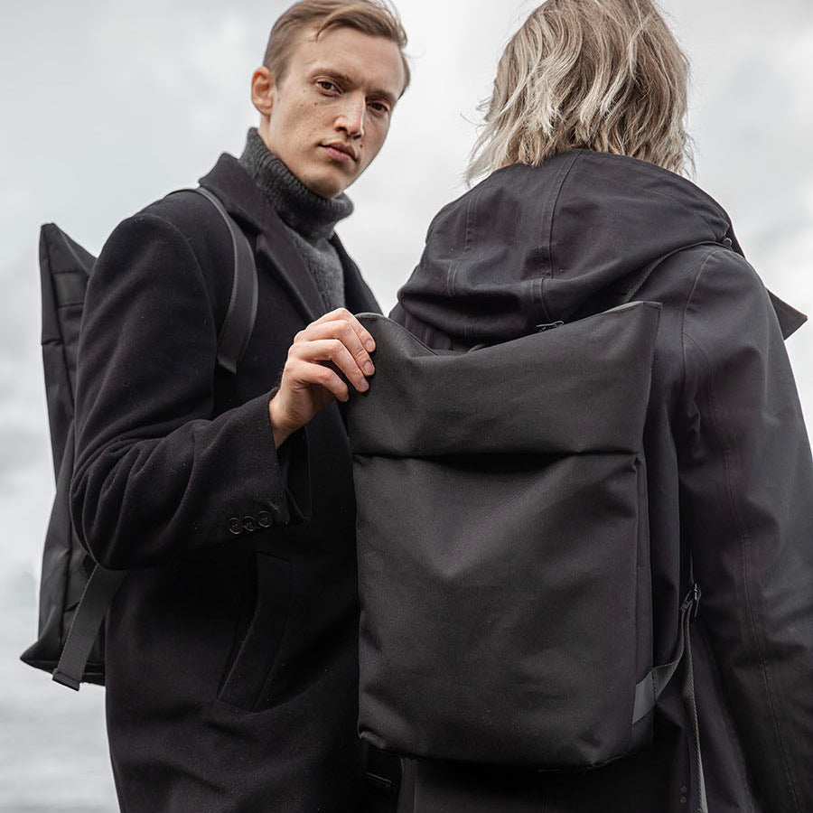 Man och kvinna en mulen dag. Mannen vänder sig mot fotografen. Man ser hennes minimalistiska vattentåliga ryggsäck i polyester.